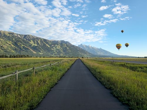 Biking towards Teton Village and Grand Teton National Park with hot air balloons flying in front